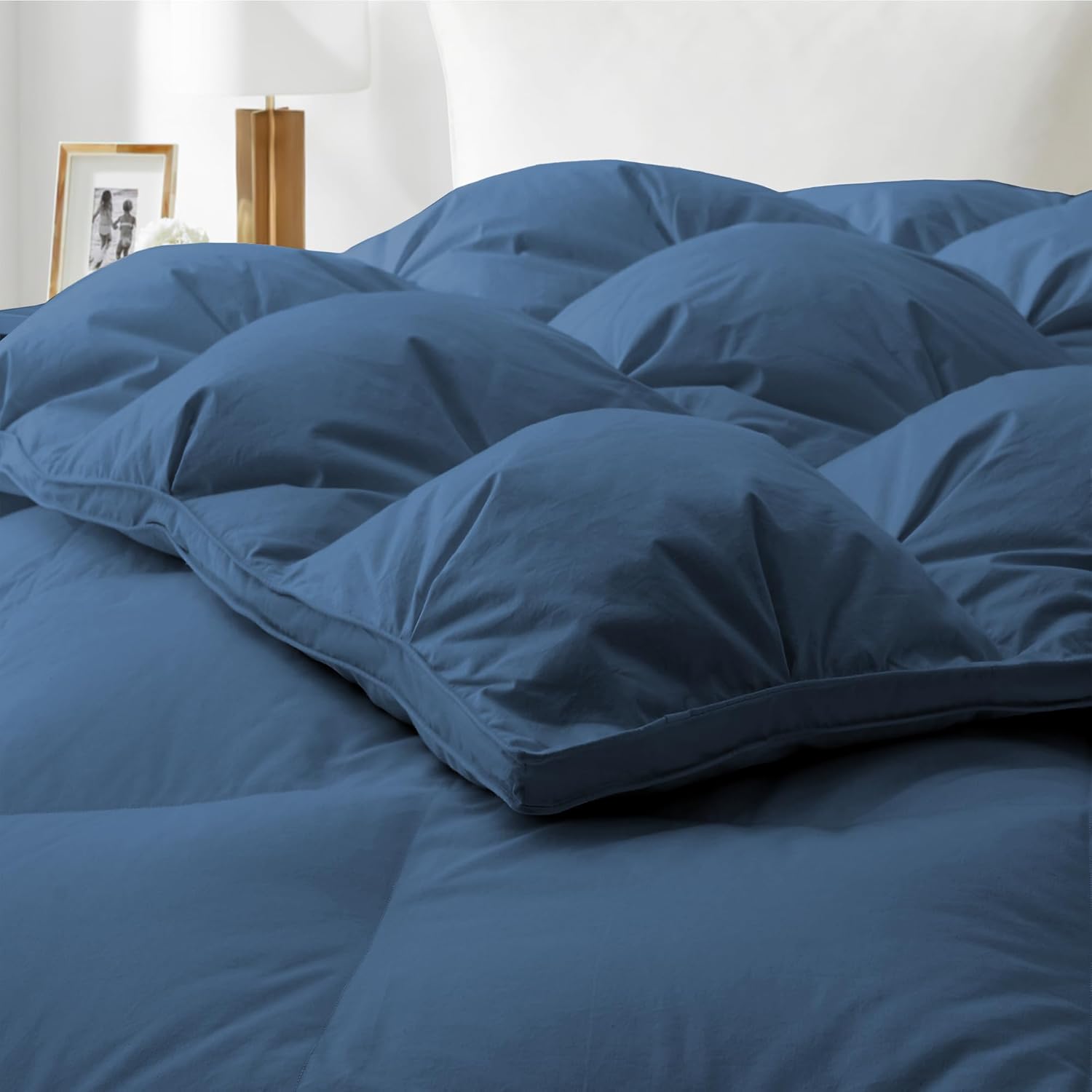 Blue comforter on a bed with a white background