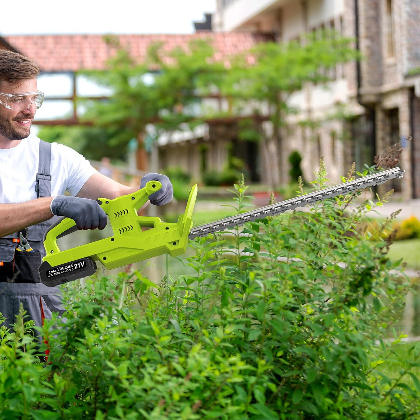 Man using a green hedge trimmer in a garden setting