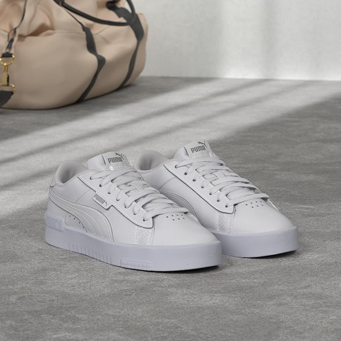 White sneakers on a gray surface with a beige bag in the background