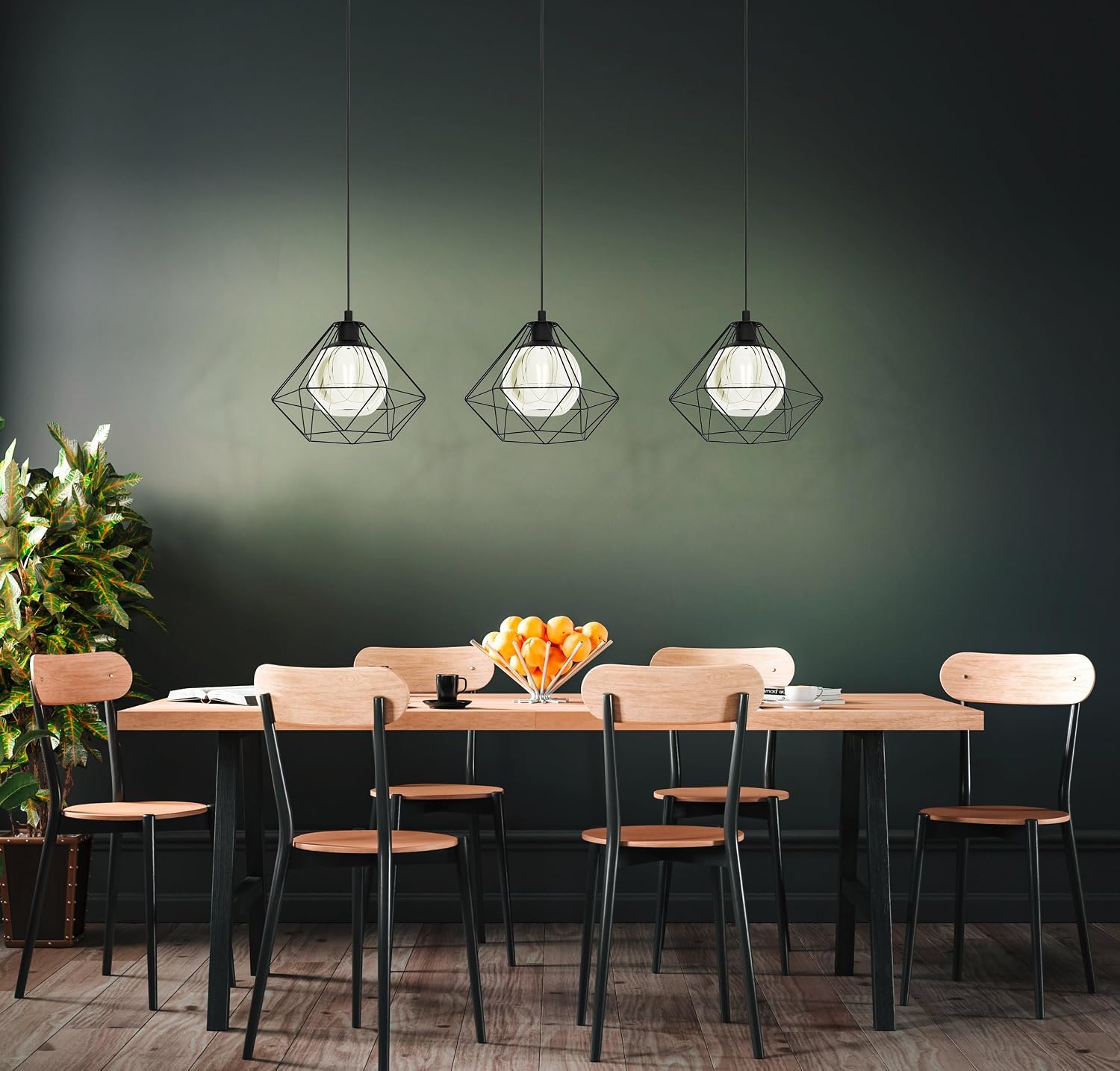 Three modern geometric wire-frame pendant lights hang above a wooden dining table with chairs in a dark green room.