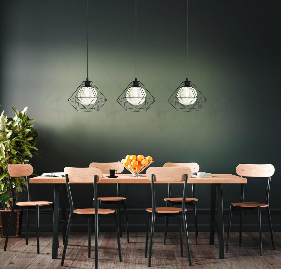 Three modern geometric wire-frame pendant lights hang above a wooden dining table with chairs in a dark green room.