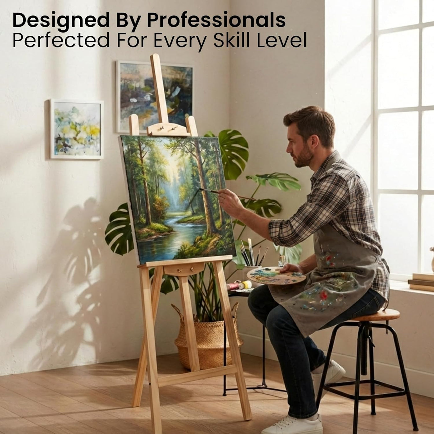 Man painting a landscape scene in a bright room with art supplies.
