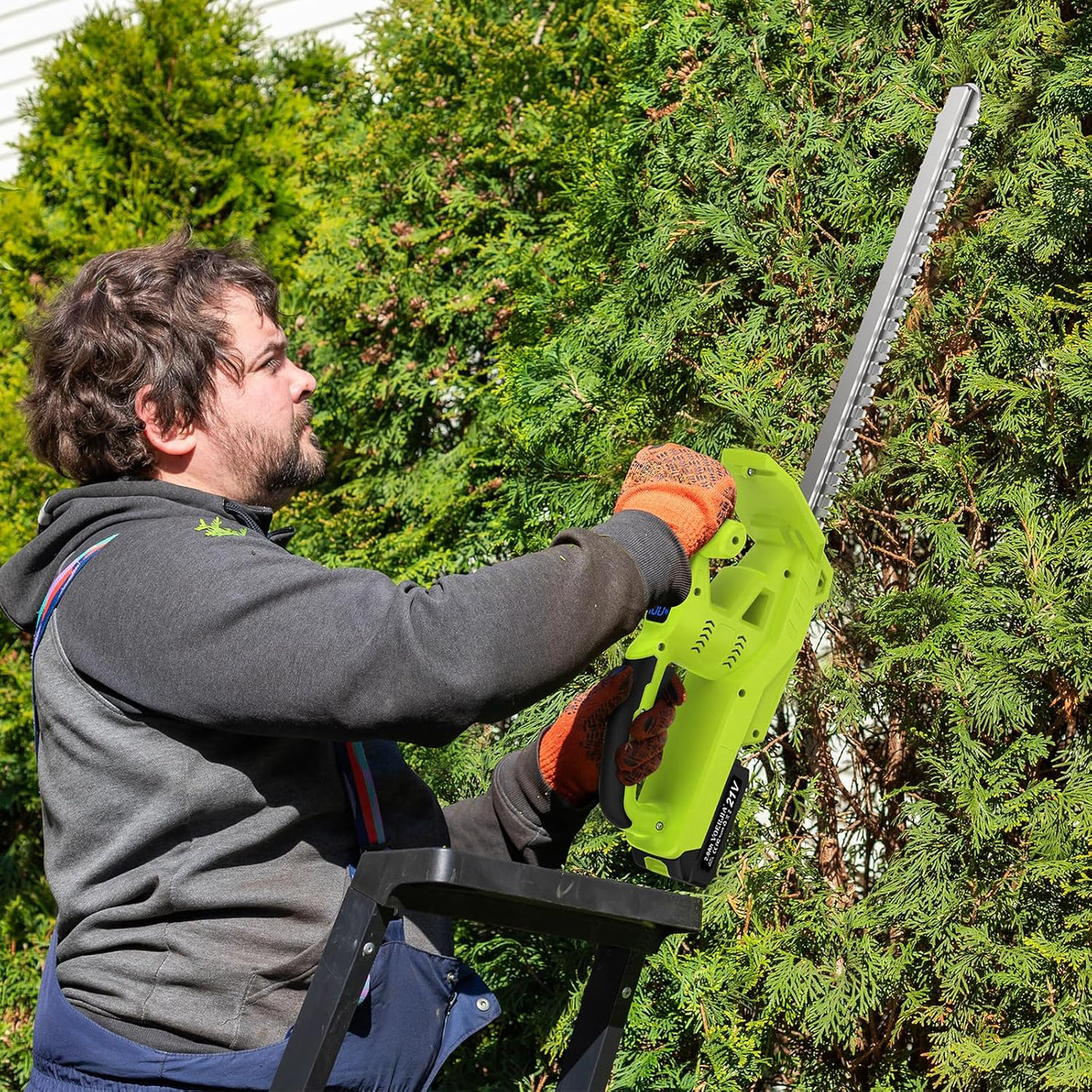 Person using a green chainsaw to trim trees