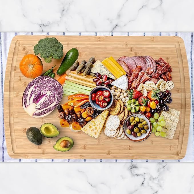 Assorted fruits, vegetables, and meats on a wooden cutting board with a marble background