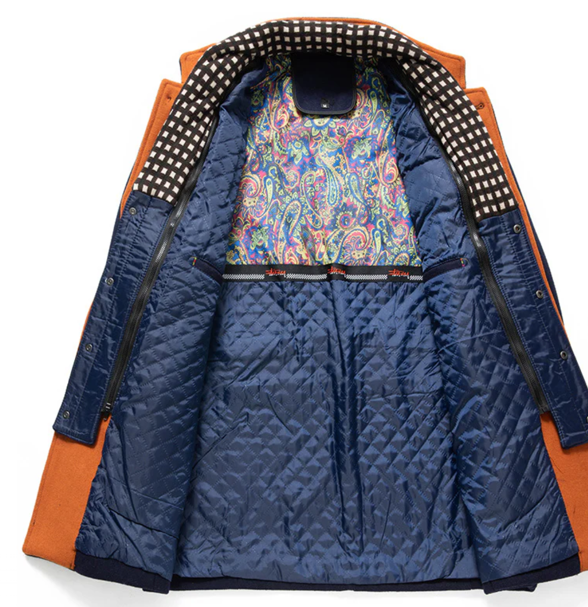 Blue quilted jacket with orange lining and colorful paisley pattern on the inside pocket.