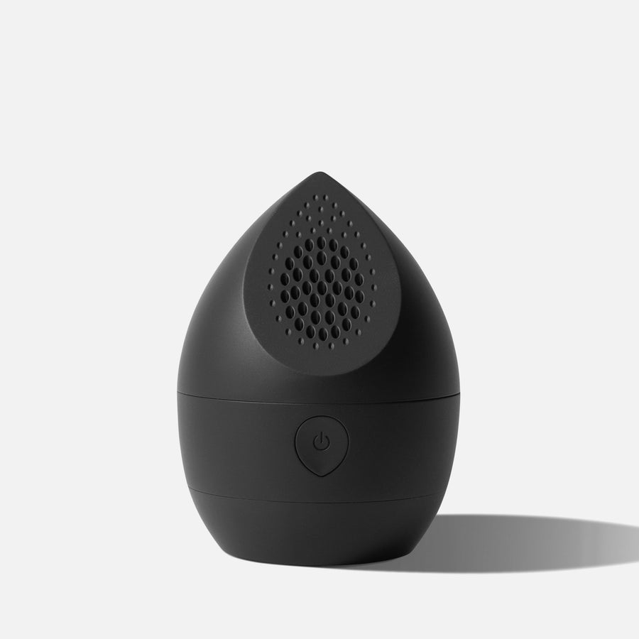 Black droplet-shaped device with a textured surface and power button on a light gray background