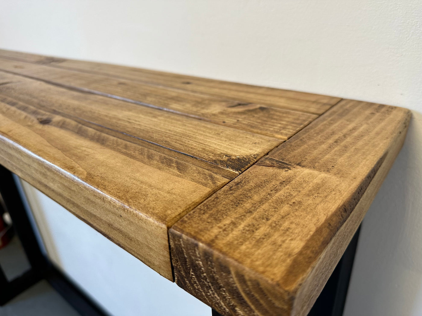 Wooden bench with a rustic finish against a white wall