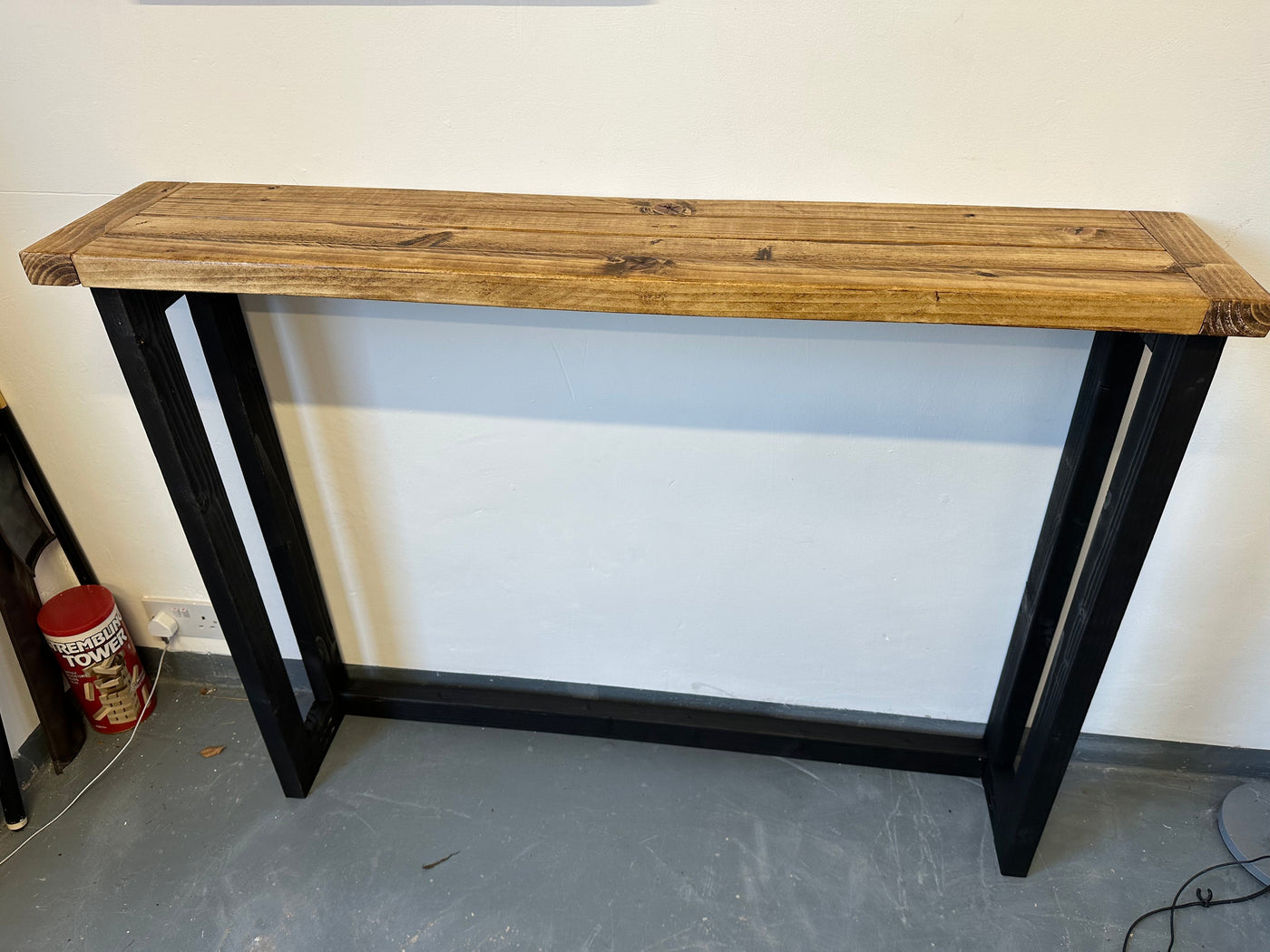 Wooden table with black metal legs against a white wall.