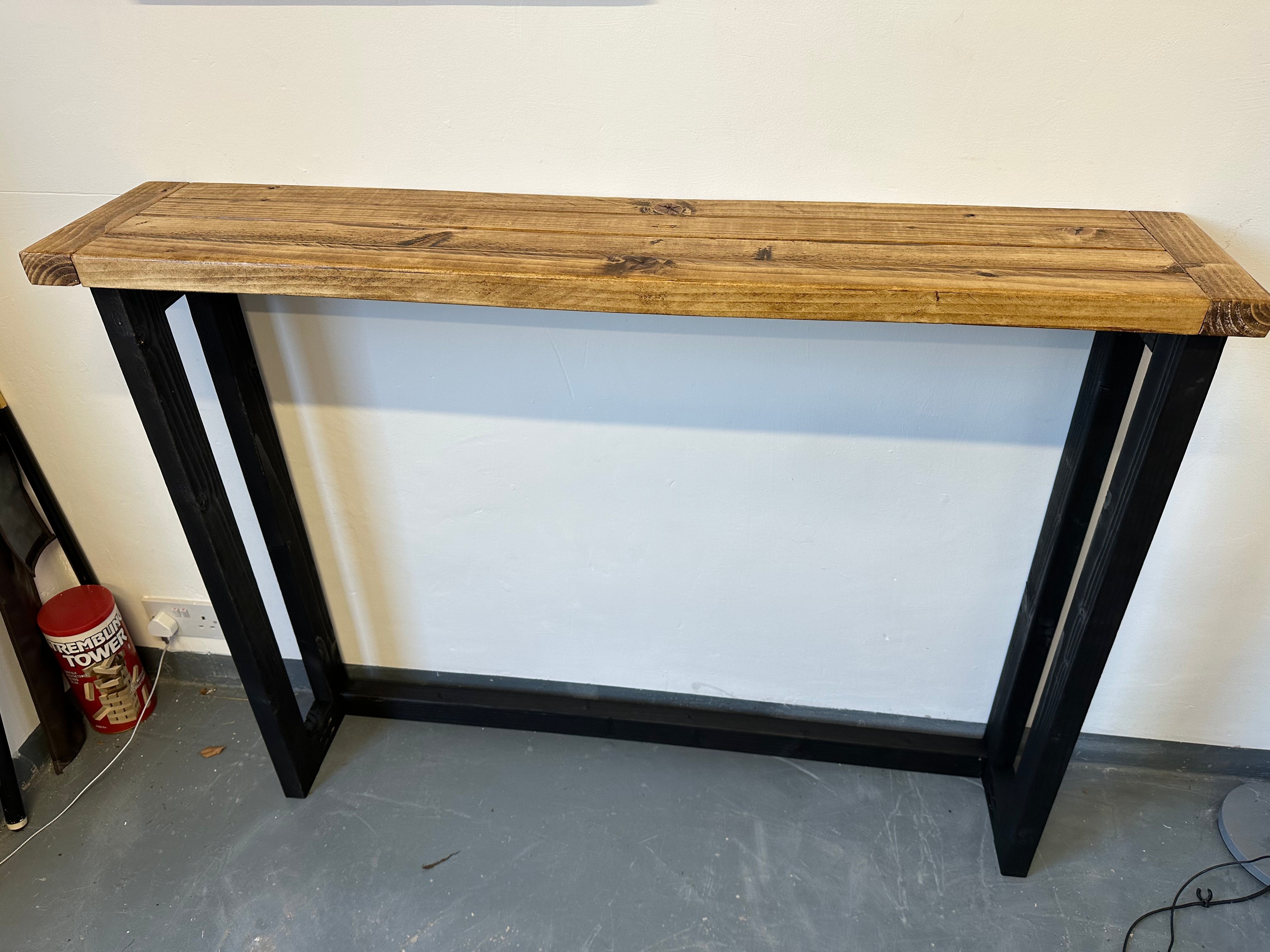 Wooden table with black metal legs against a white wall.
