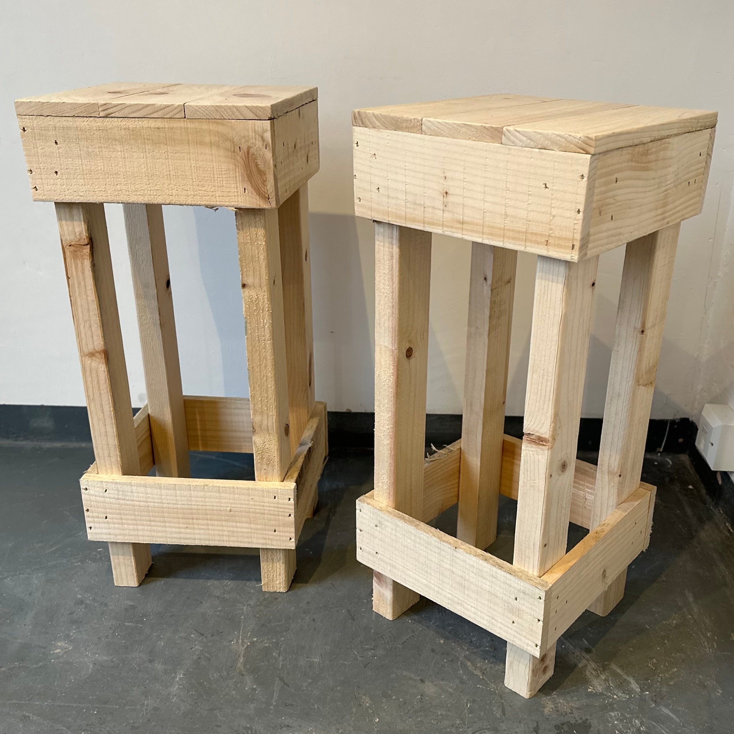 Two wooden stools on a gray floor with a plain background