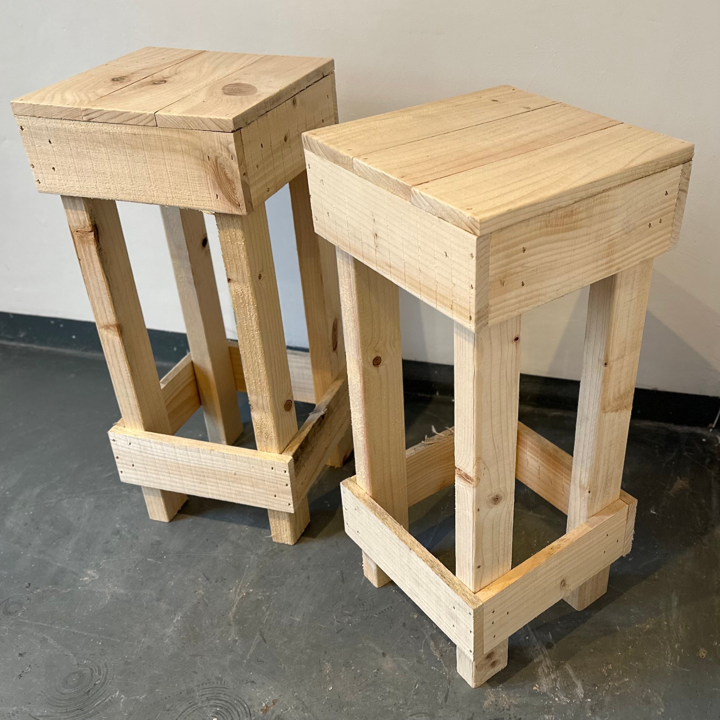 Two wooden stools on a gray floor with a neutral background