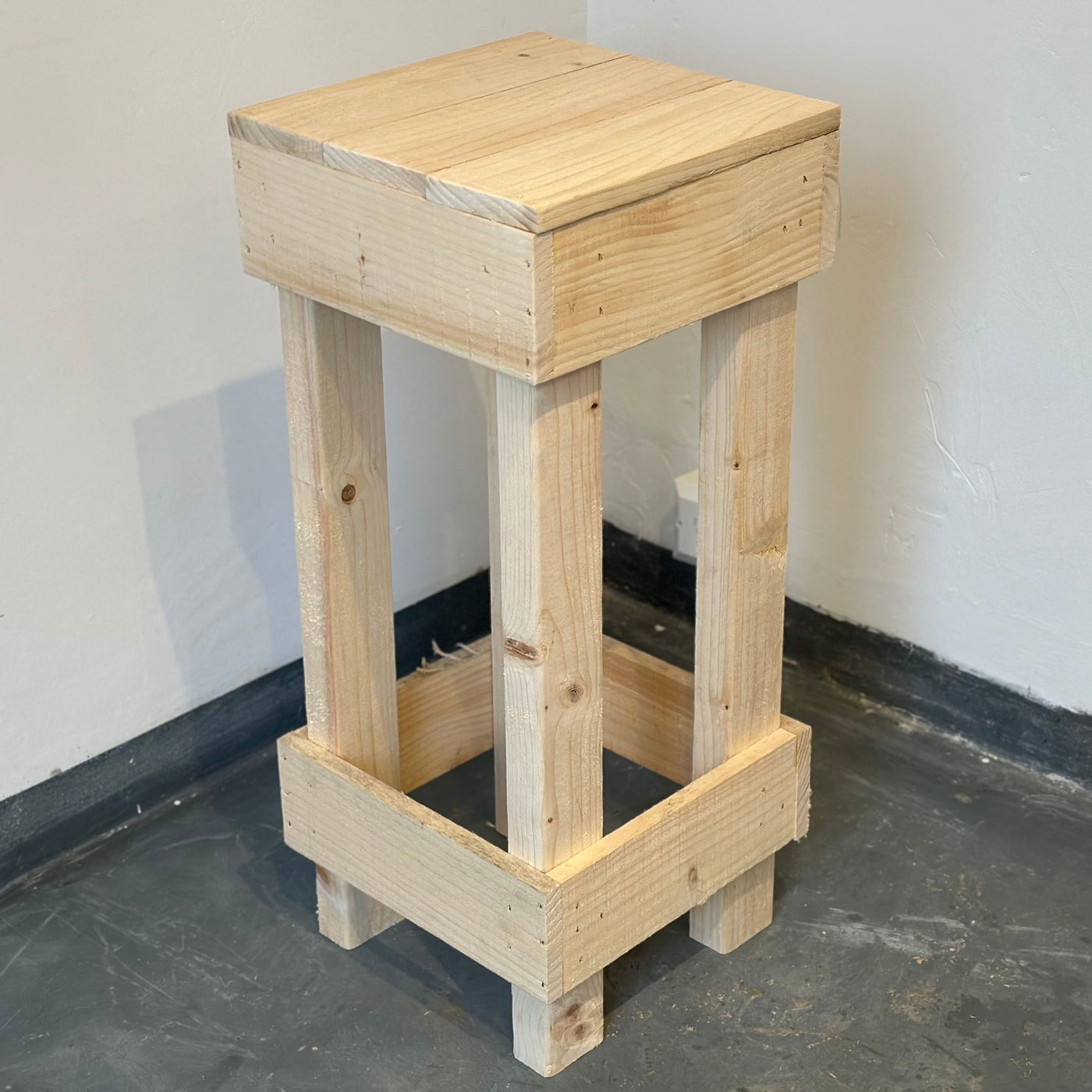 Wooden stool against a white wall