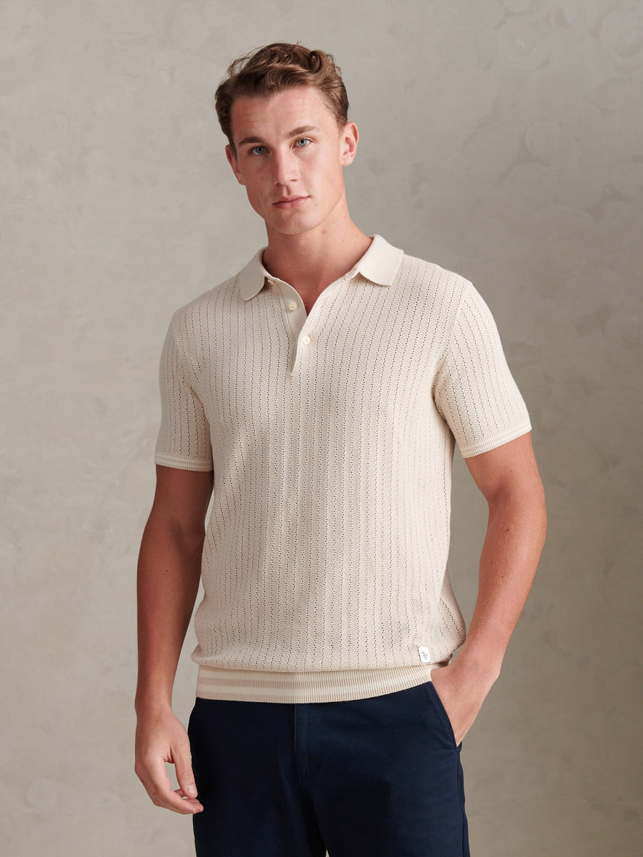 Man wearing a beige ribbed polo shirt against a neutral background