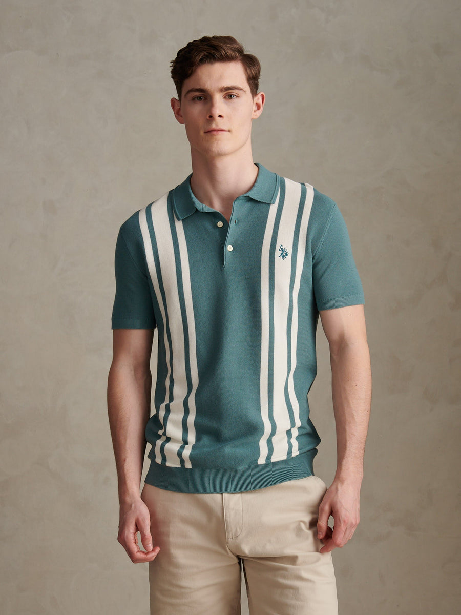 Man wearing a green and white striped polo shirt against a beige background