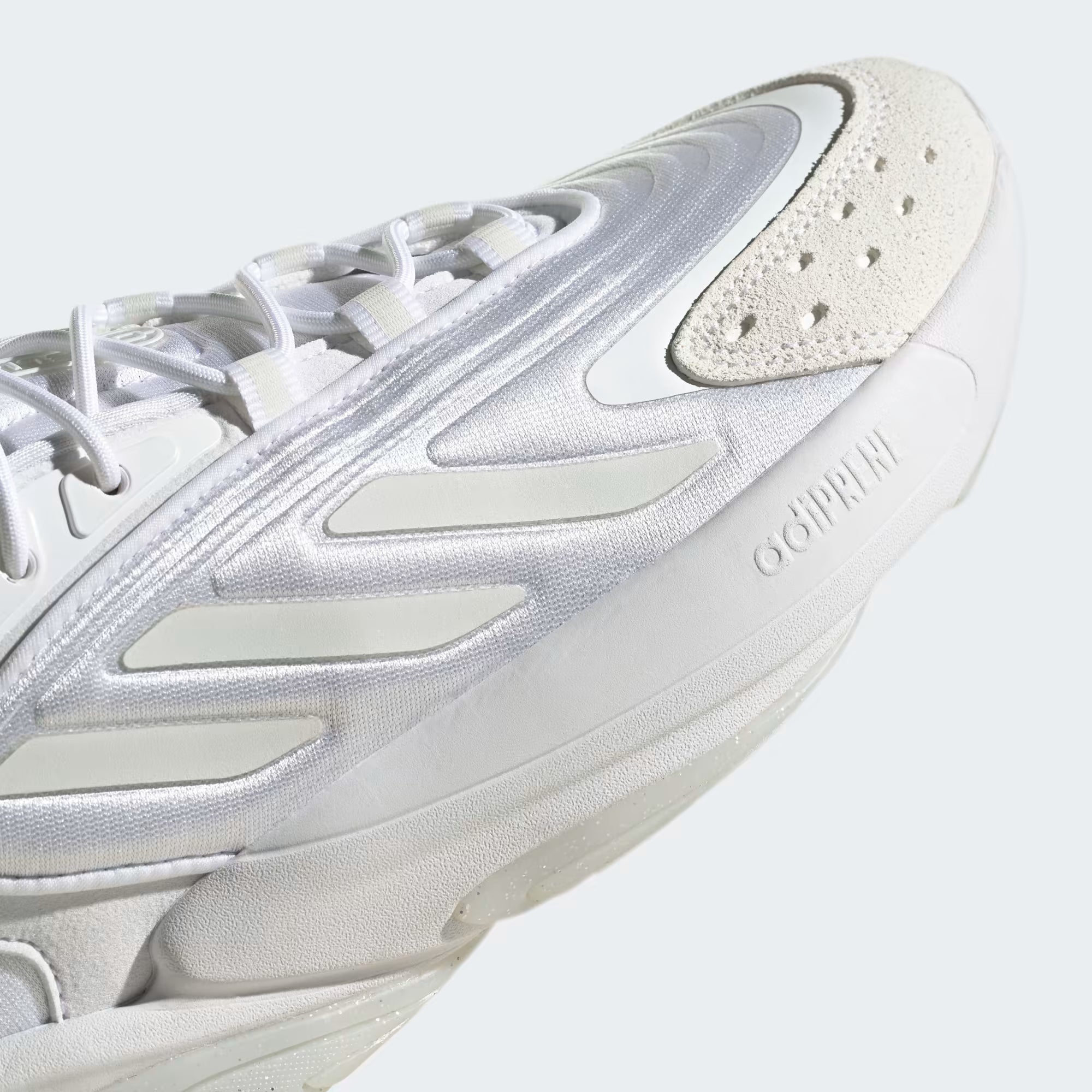 Close-up of a white sneaker with a light gray sole on a light gray background
