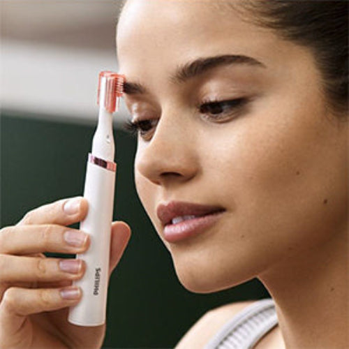 Woman holding a white and pink electric toothbrush close to her face.