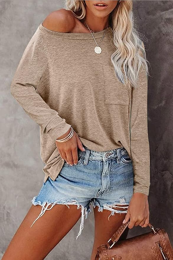 Woman wearing a beige off-shoulder top and denim shorts against a gray background