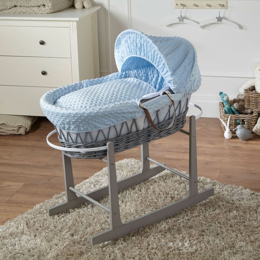 Baby Moses basket with blue and white pattern on a stand in a nursery setting.