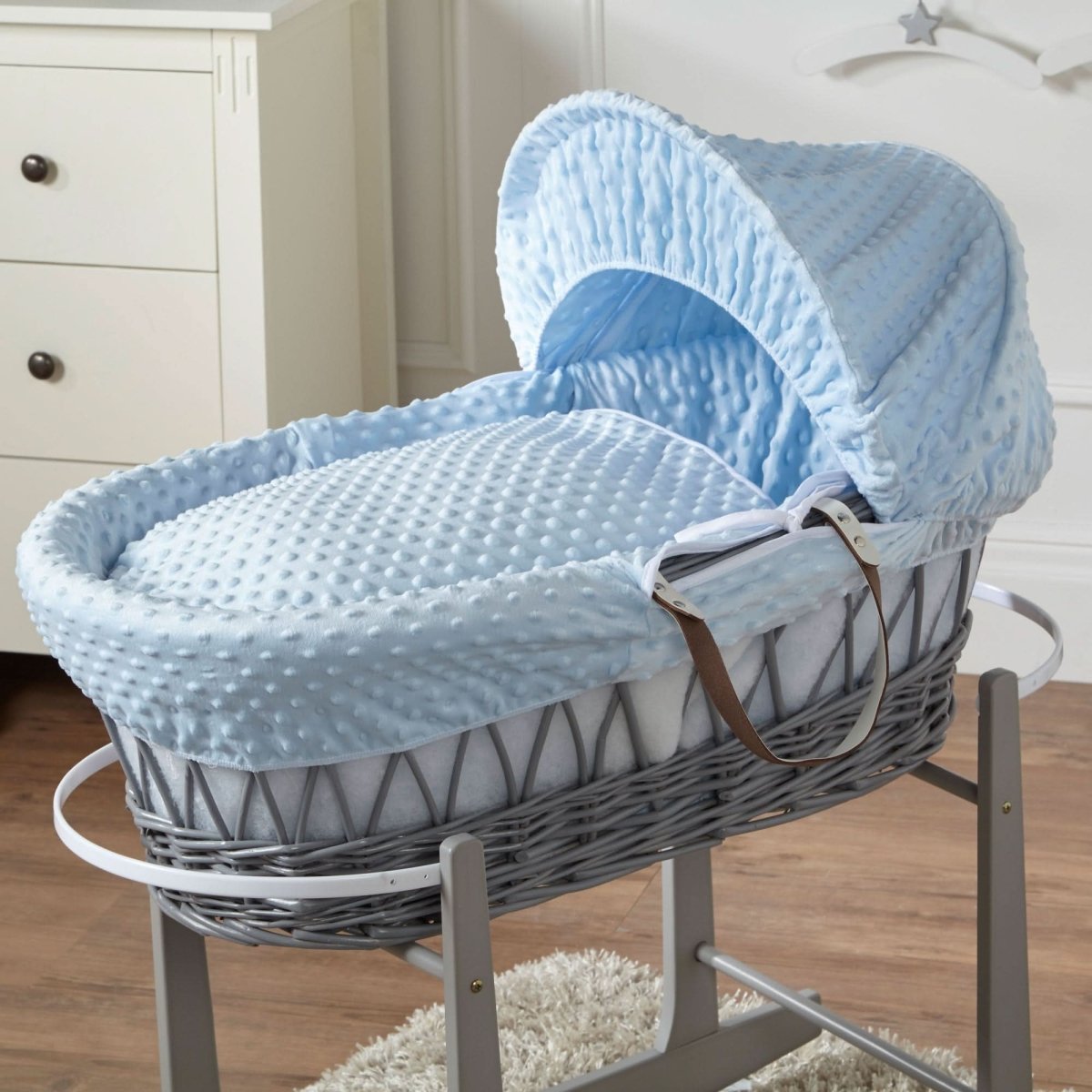Gray wicker baby Moses basket with blue cover in a room setting