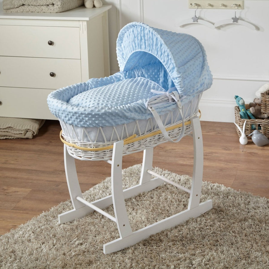 Baby Moses basket with blue cover on a stand in a nursery setting