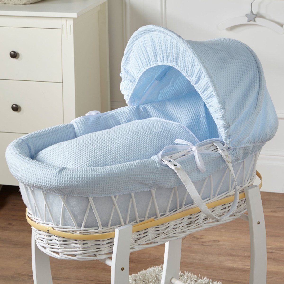 Baby Moses basket with blue cover in a nursery setting