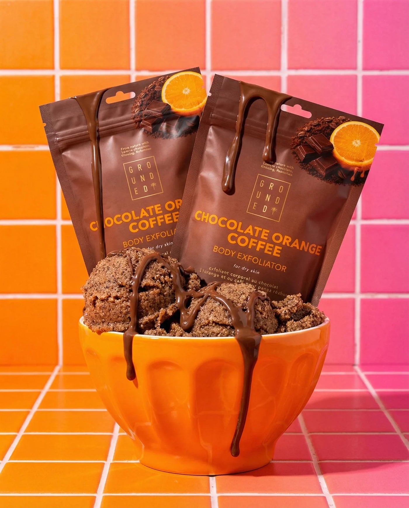 Chocolate orange coffee body exfoliator with packaging on an orange and pink tiled background
