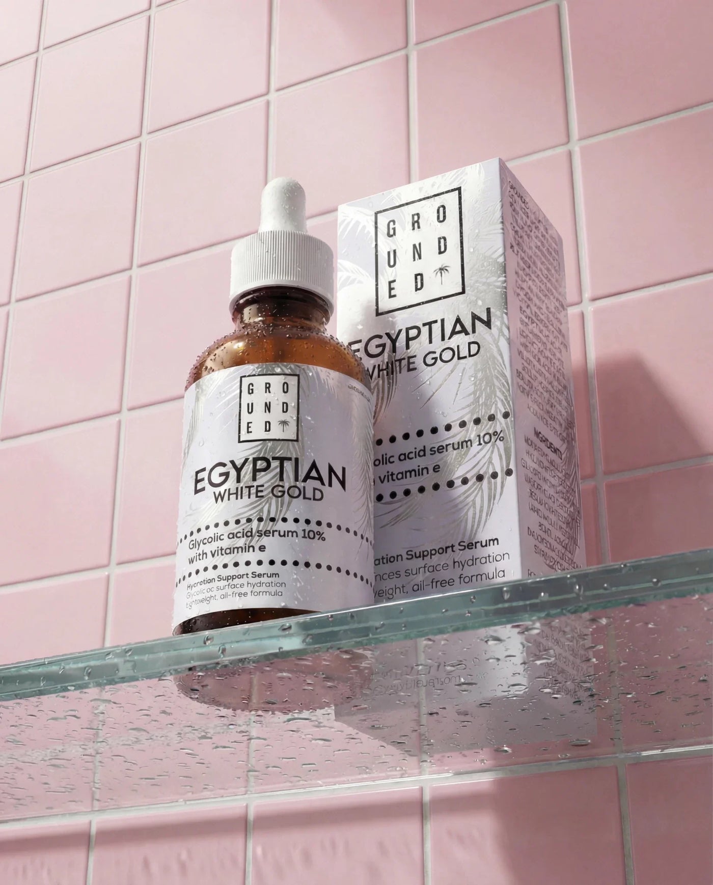 Grounded Egyptian White Gold skincare product on a glass shelf with pink tiled wall background