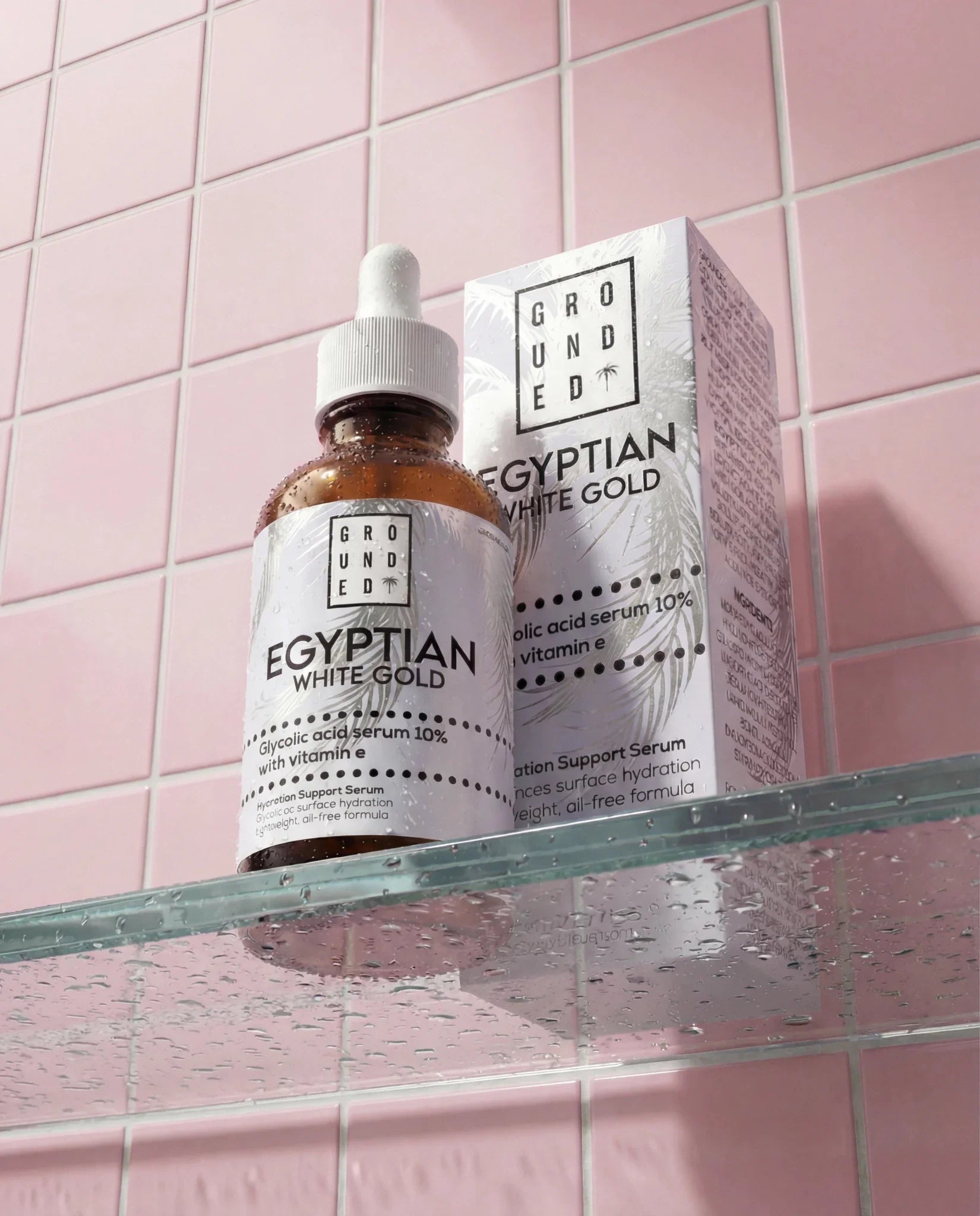 Grounded Egyptian White Gold skincare product on a glass shelf with pink tiled wall background