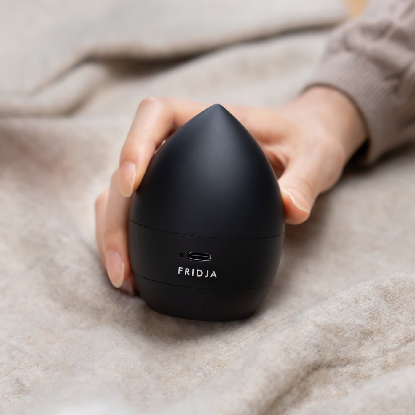 Person holding a black Fridja product on a soft surface