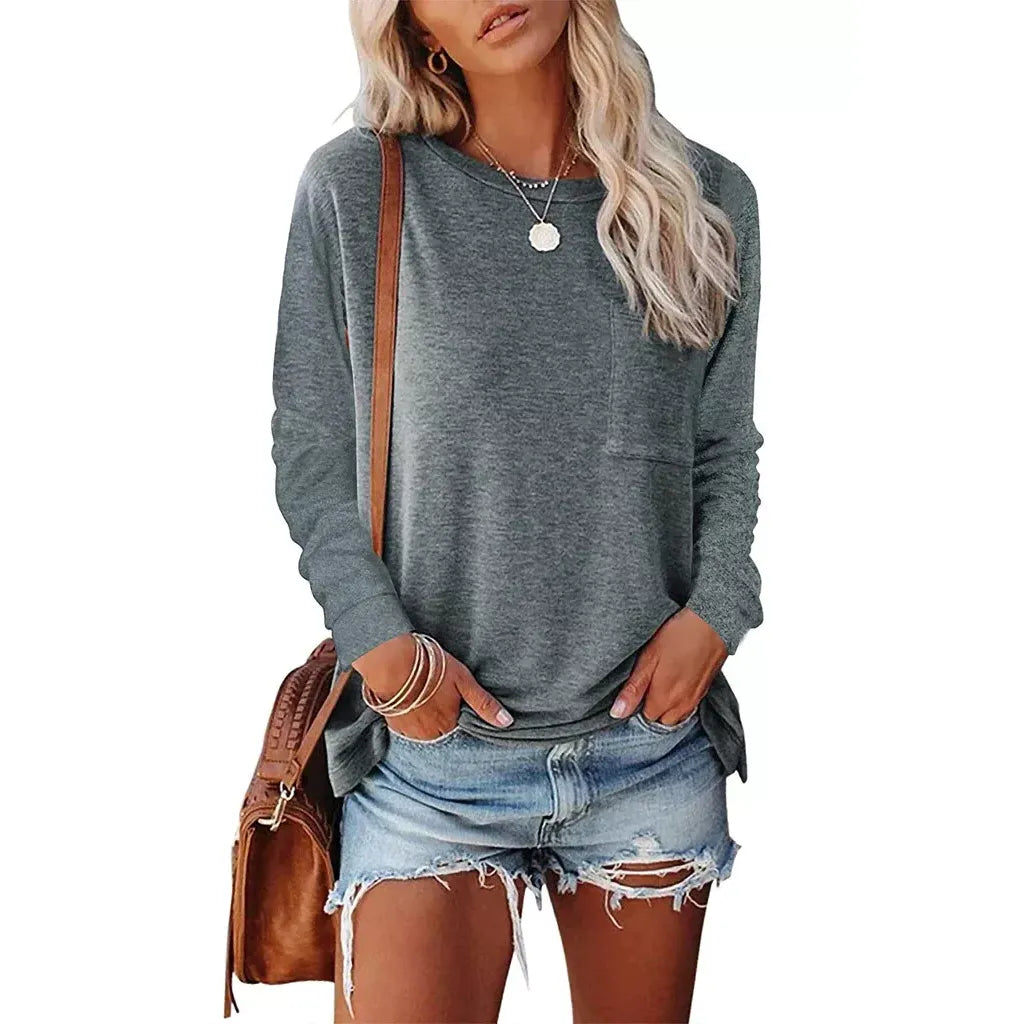 Woman wearing a gray long-sleeve top and denim shorts, holding a brown bag on a white background
