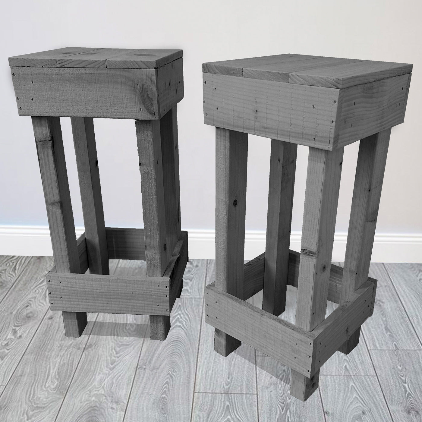 Two gray wooden stools on a light wood floor with a white wall background