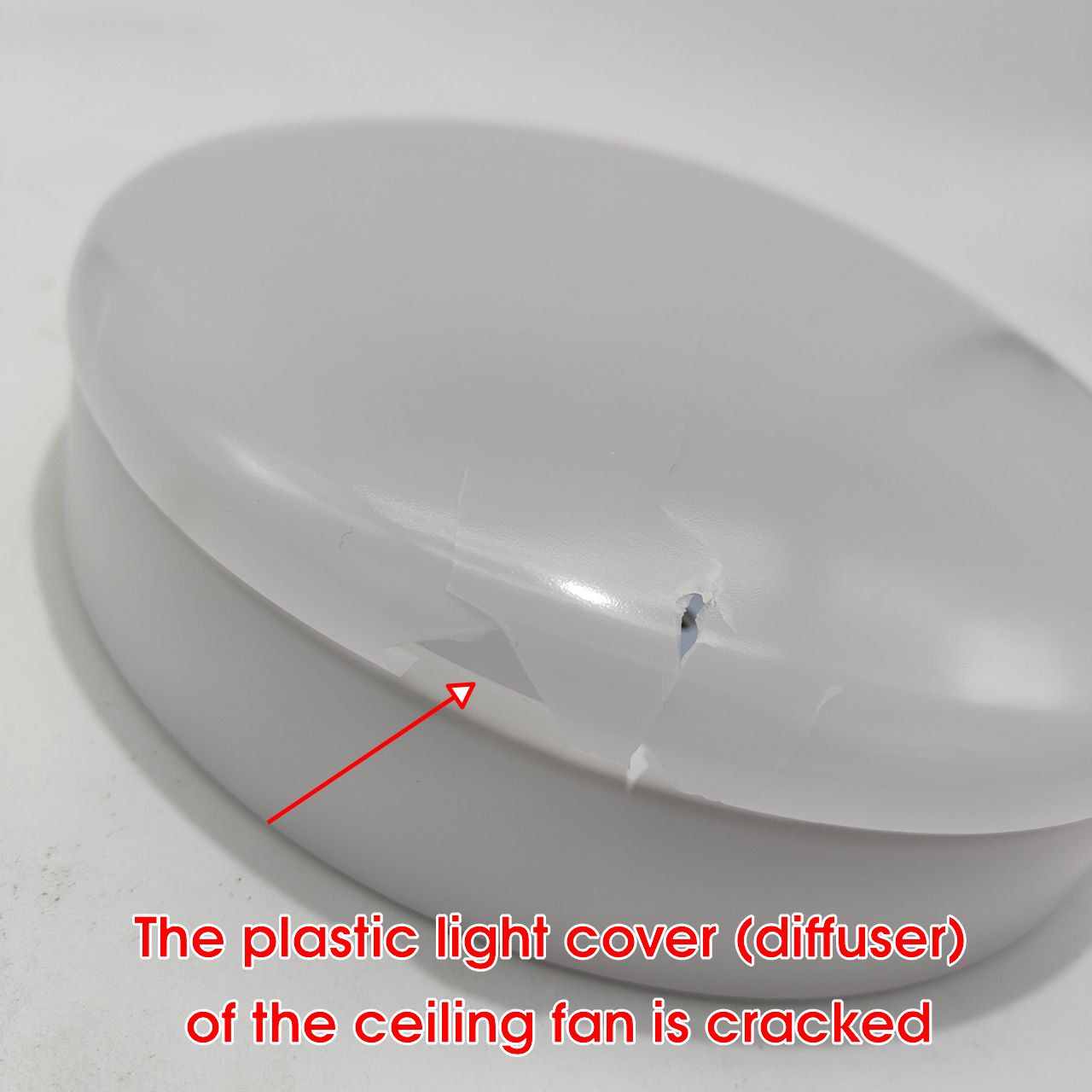 Cracked plastic light cover of a ceiling fan on a white background