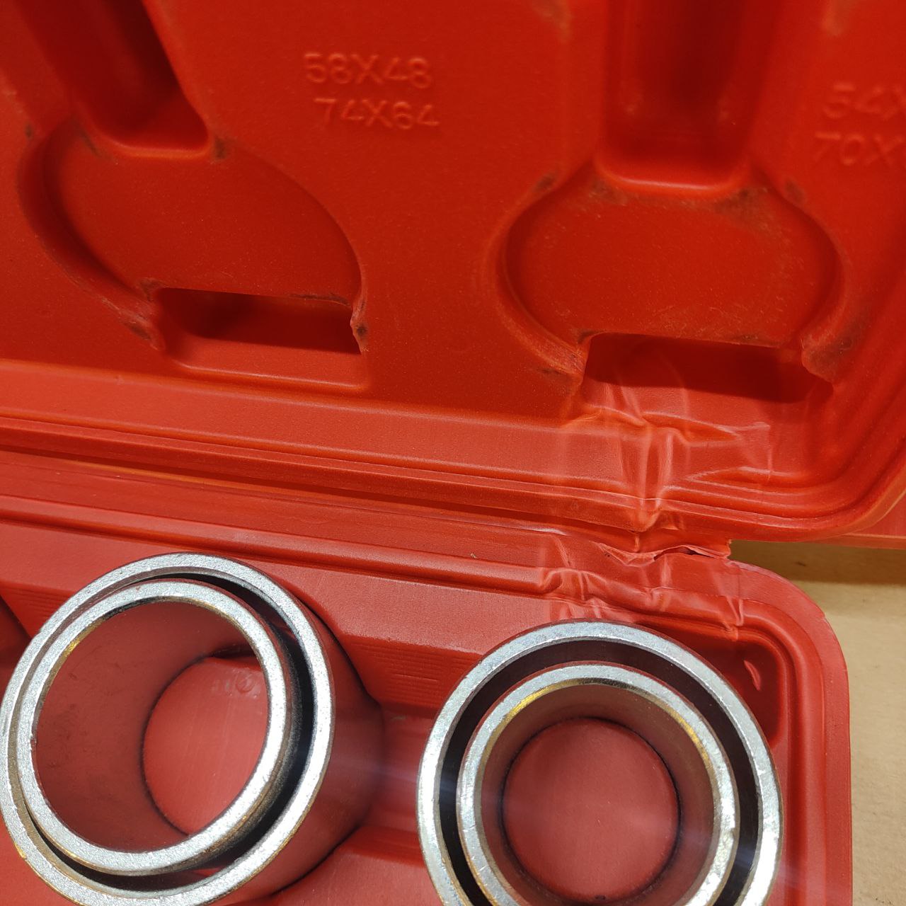 Two metal bearings in front of an open red toolbox.