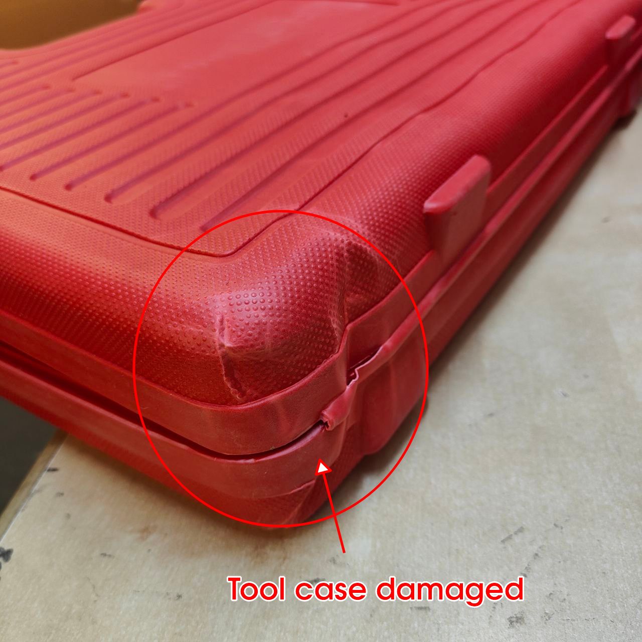 Red tool case with a visible dent, labeled 'Tool case damaged', on a concrete surface.