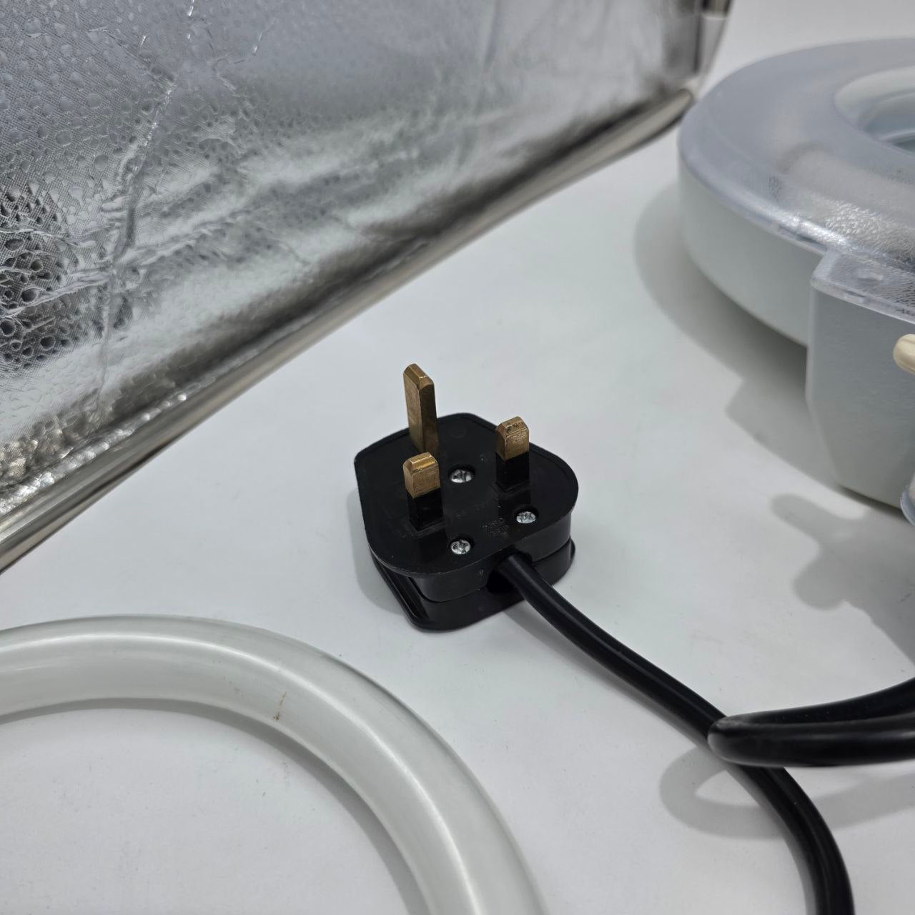 Black plug on a white surface with a clear container in the background