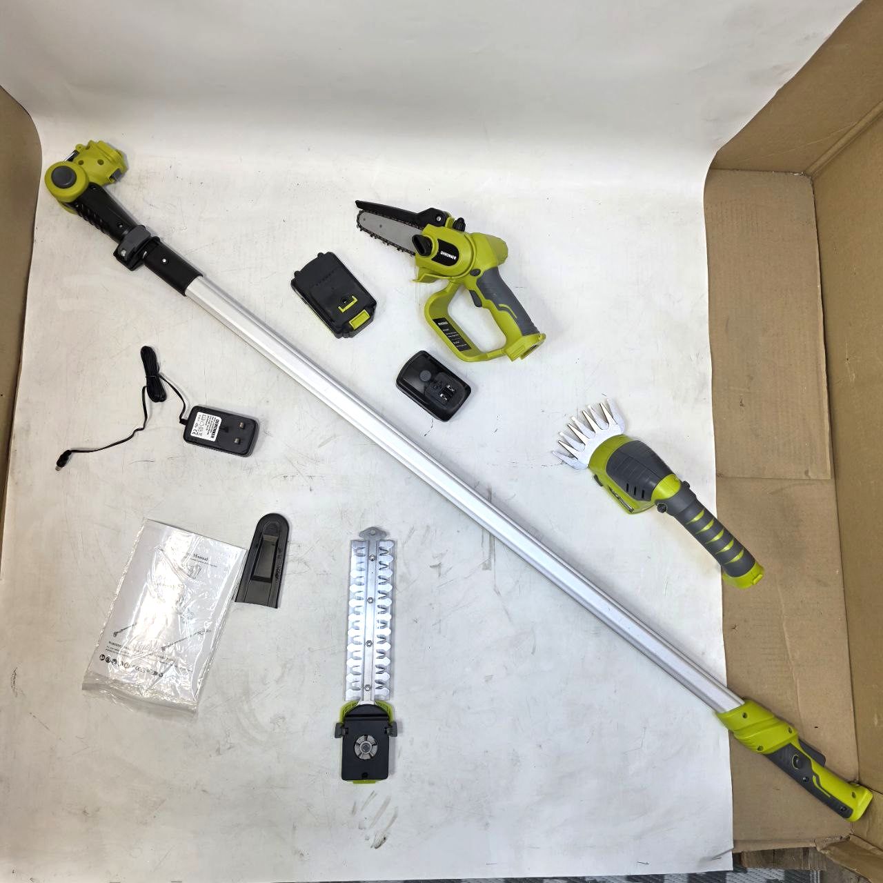 Gardening tools including a pole pruner and hedge trimmer on a white surface.