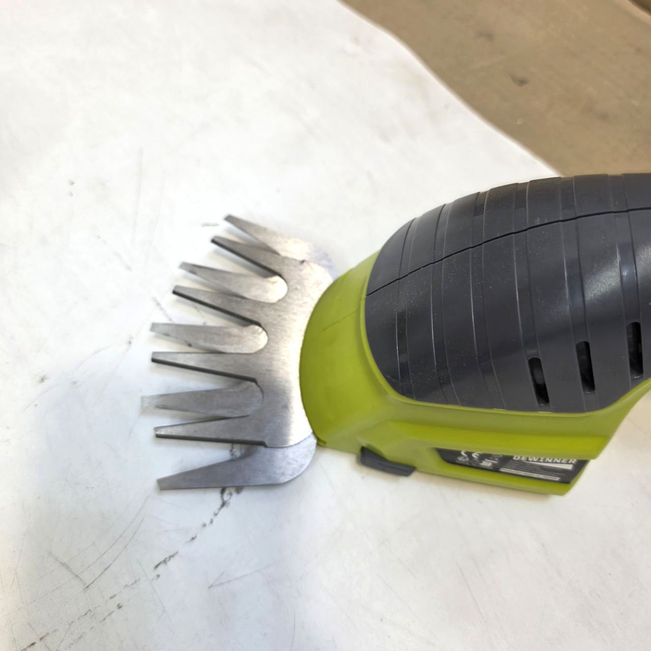 Green grooming tool with metal teeth on a white surface