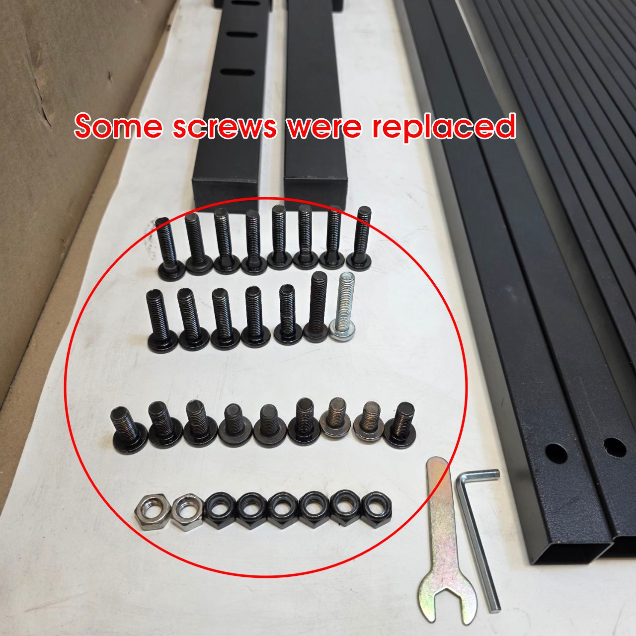 Collection of screws, bolts, and nuts on a white surface with metal brackets.