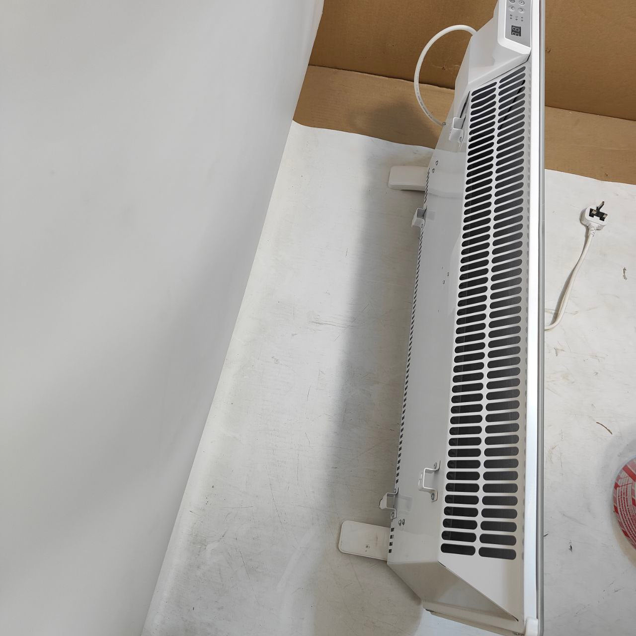 Wall-mounted air conditioner on a white wall with a cardboard box in the background