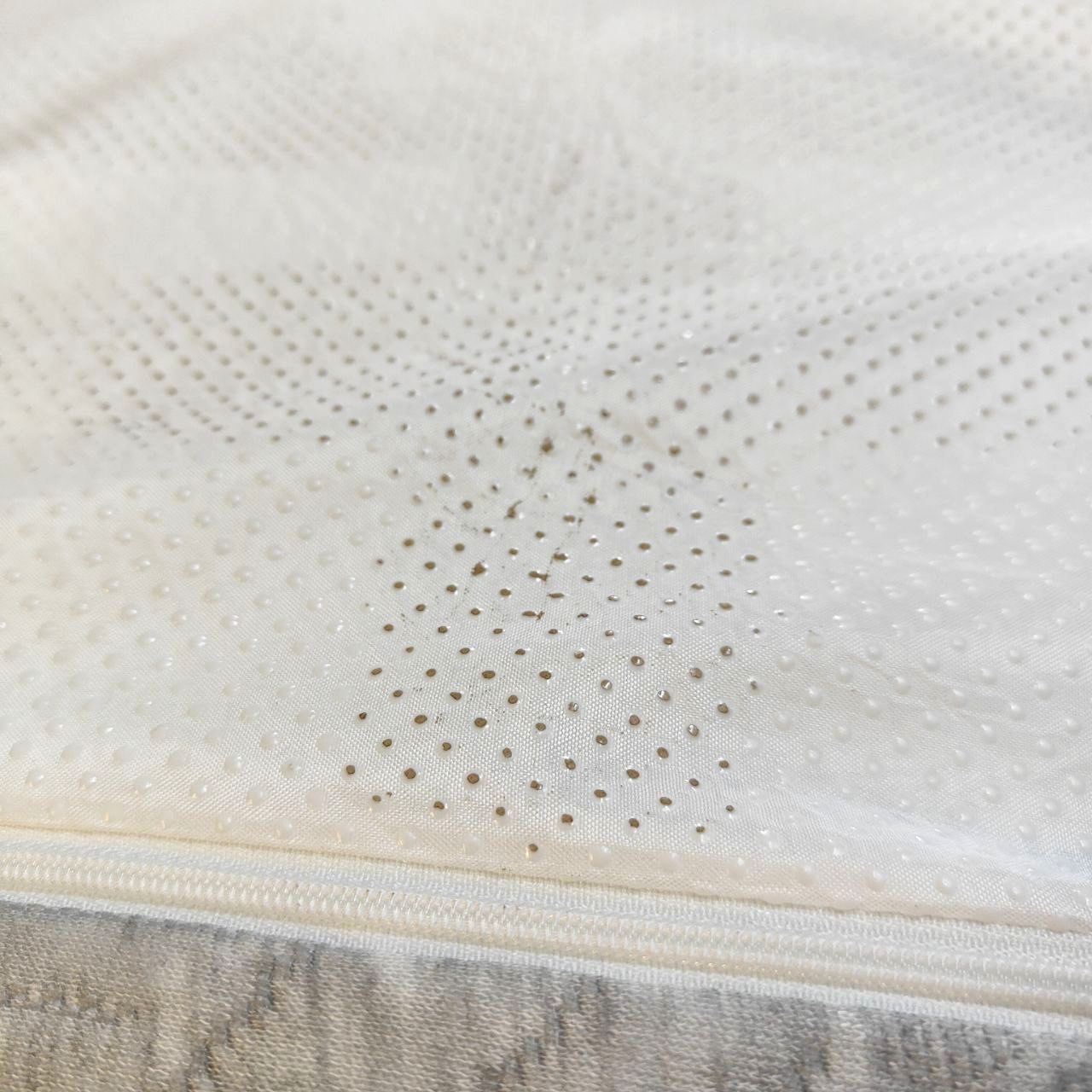 Close-up of a textured mattress surface with a zipper detail.
