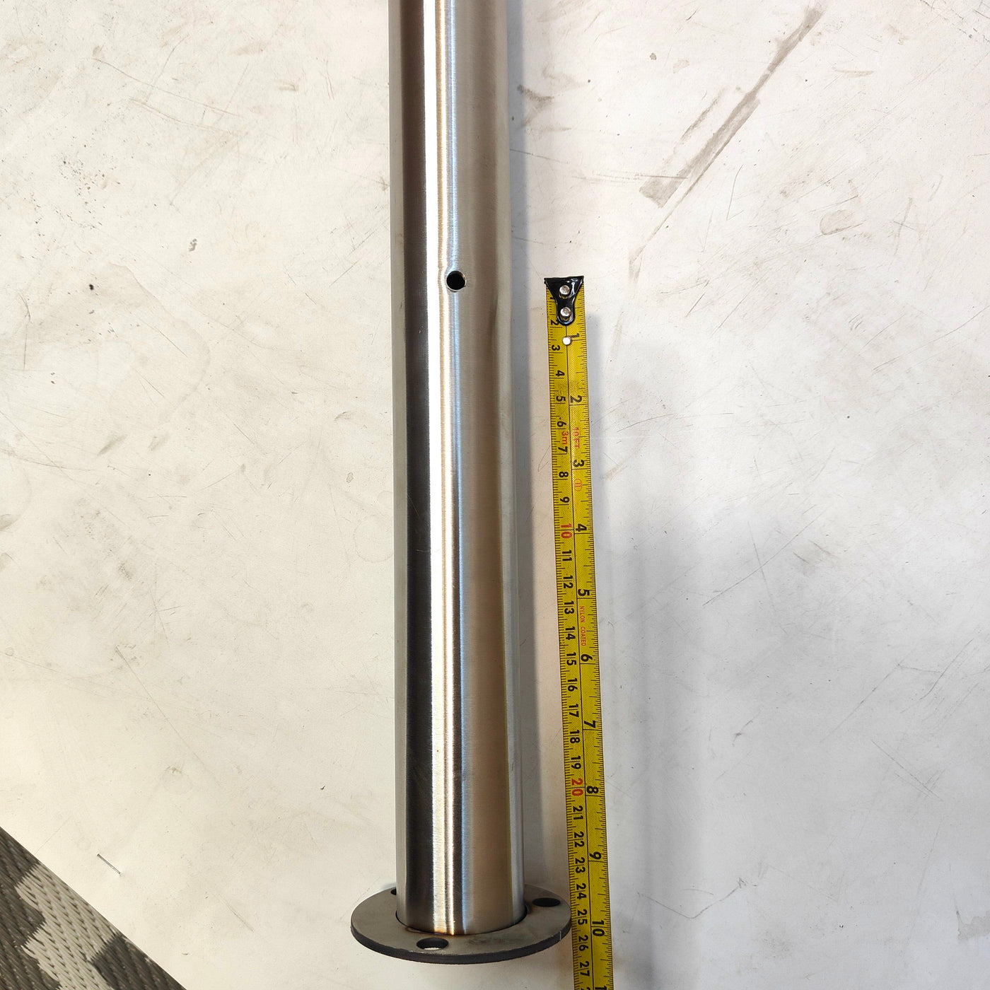 Metal cylindrical object with a tape measure for scale on a white background