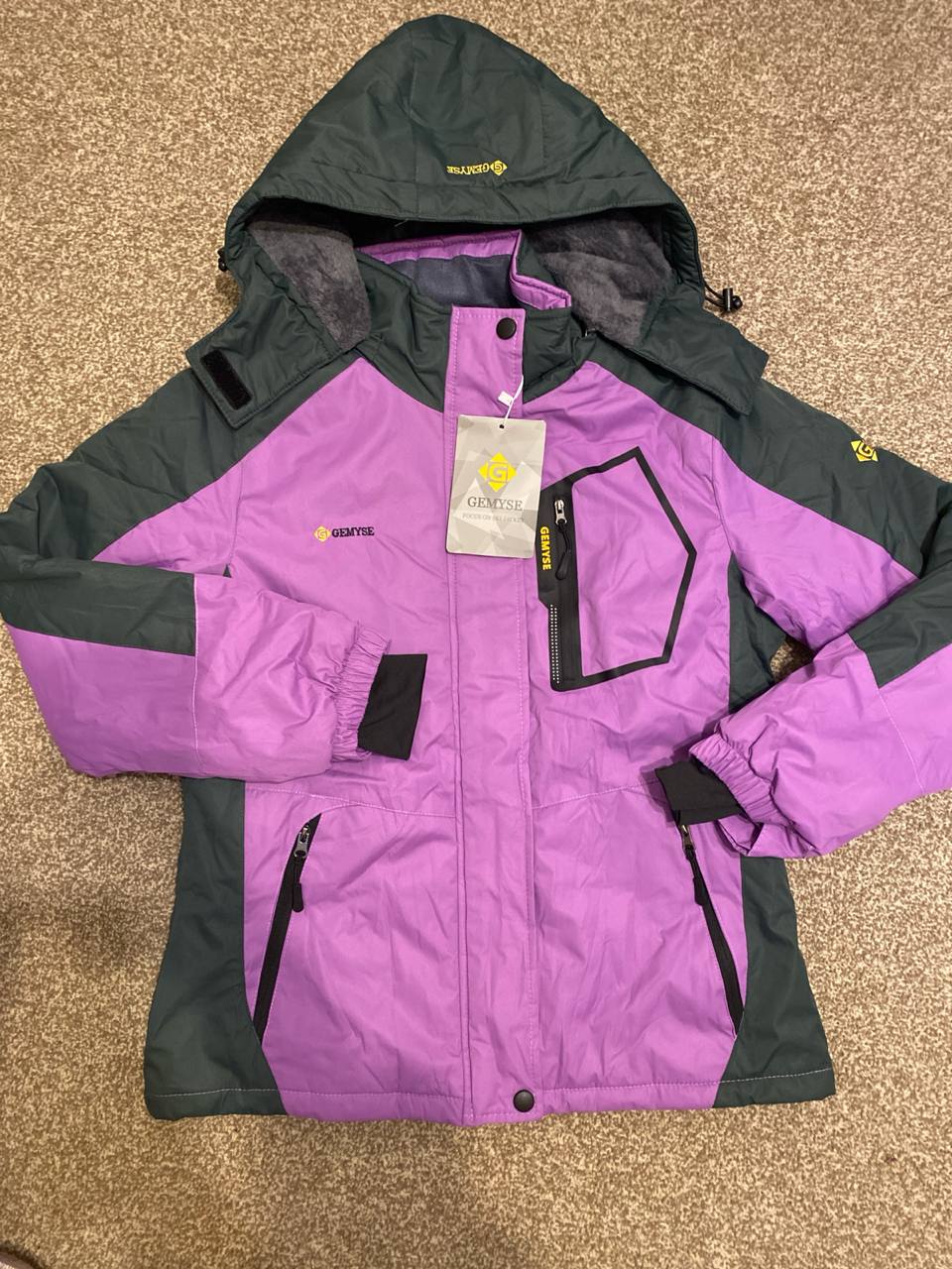 Purple and gray jacket with a brand tag on a beige carpet