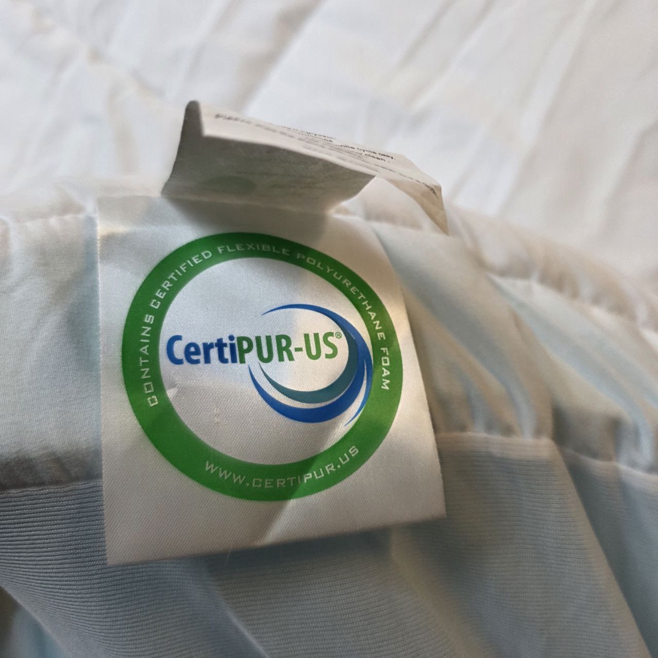 CertiPUR-US certified mattress topper packaging on a bed