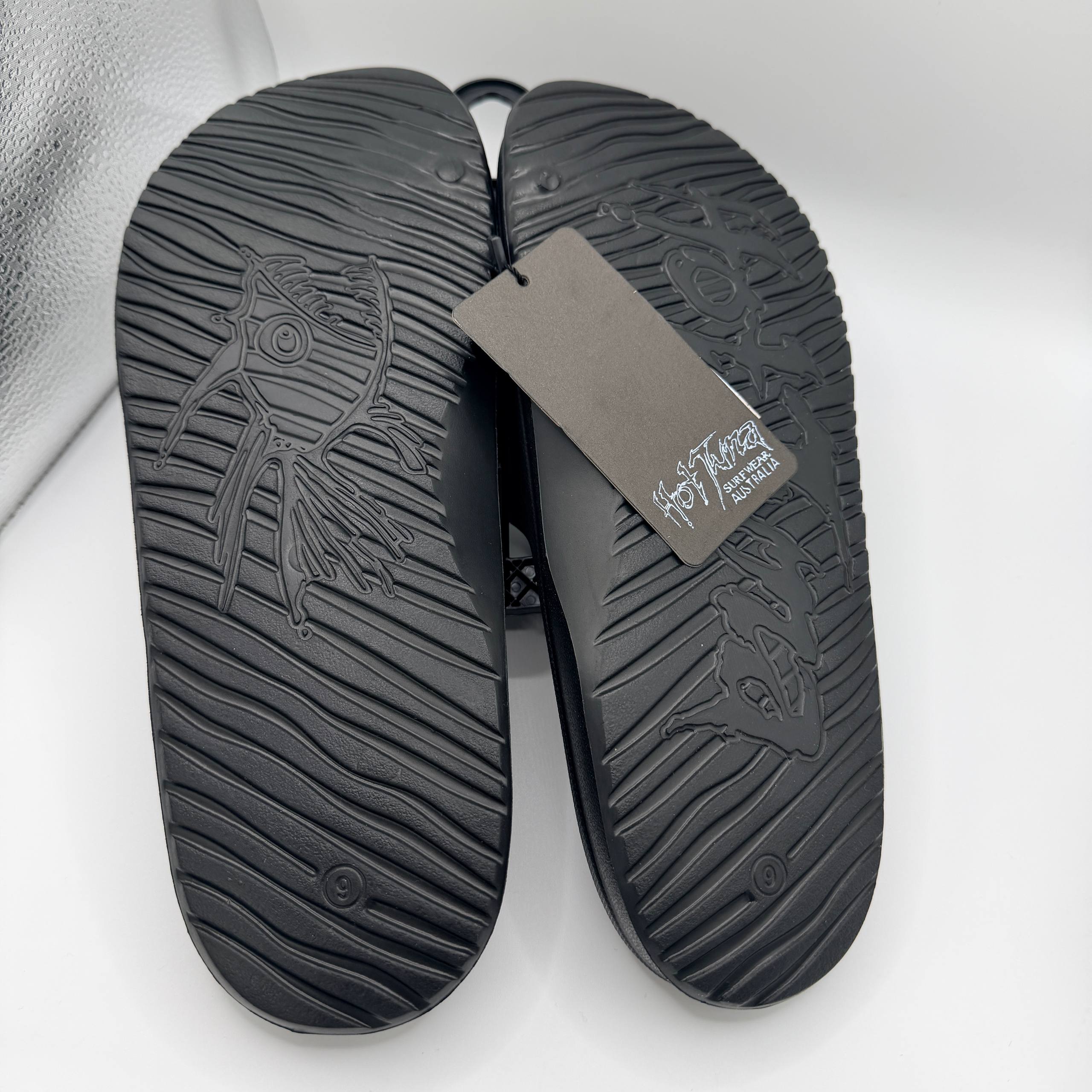 Black sandals with a brand tag on a white background