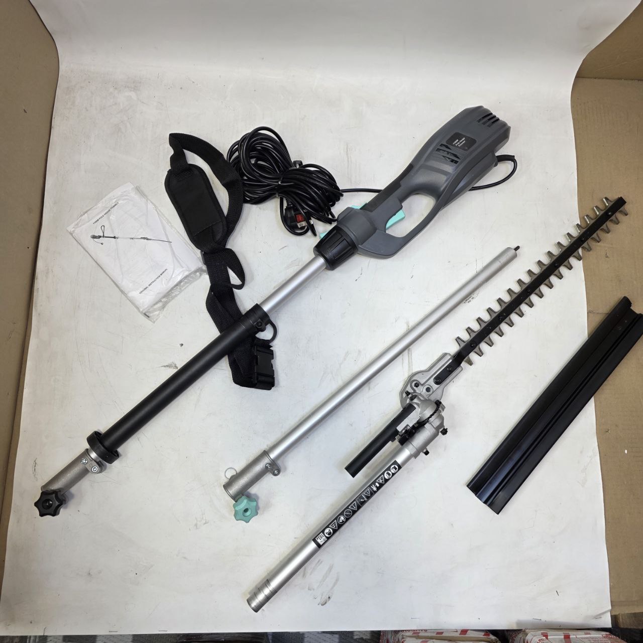 Gardening tool set with hedge trimmer, extension pole, and other components on a white surface.