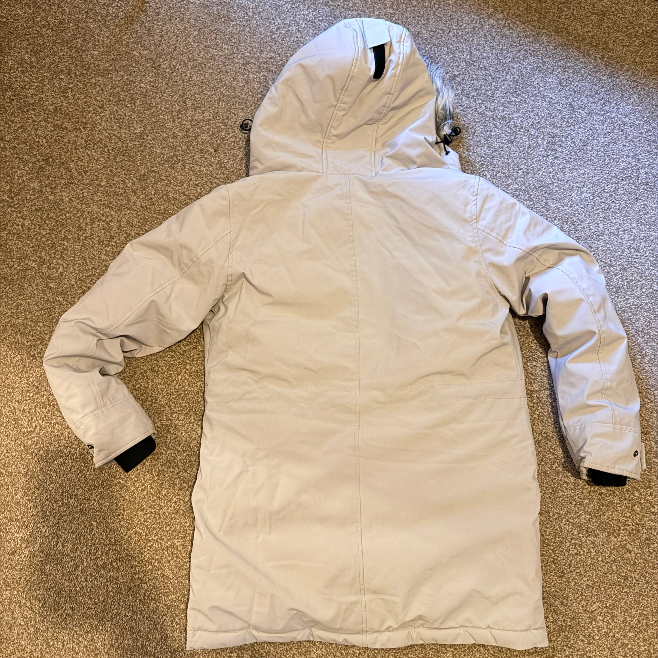 Beige winter jacket with a hood on a textured surface