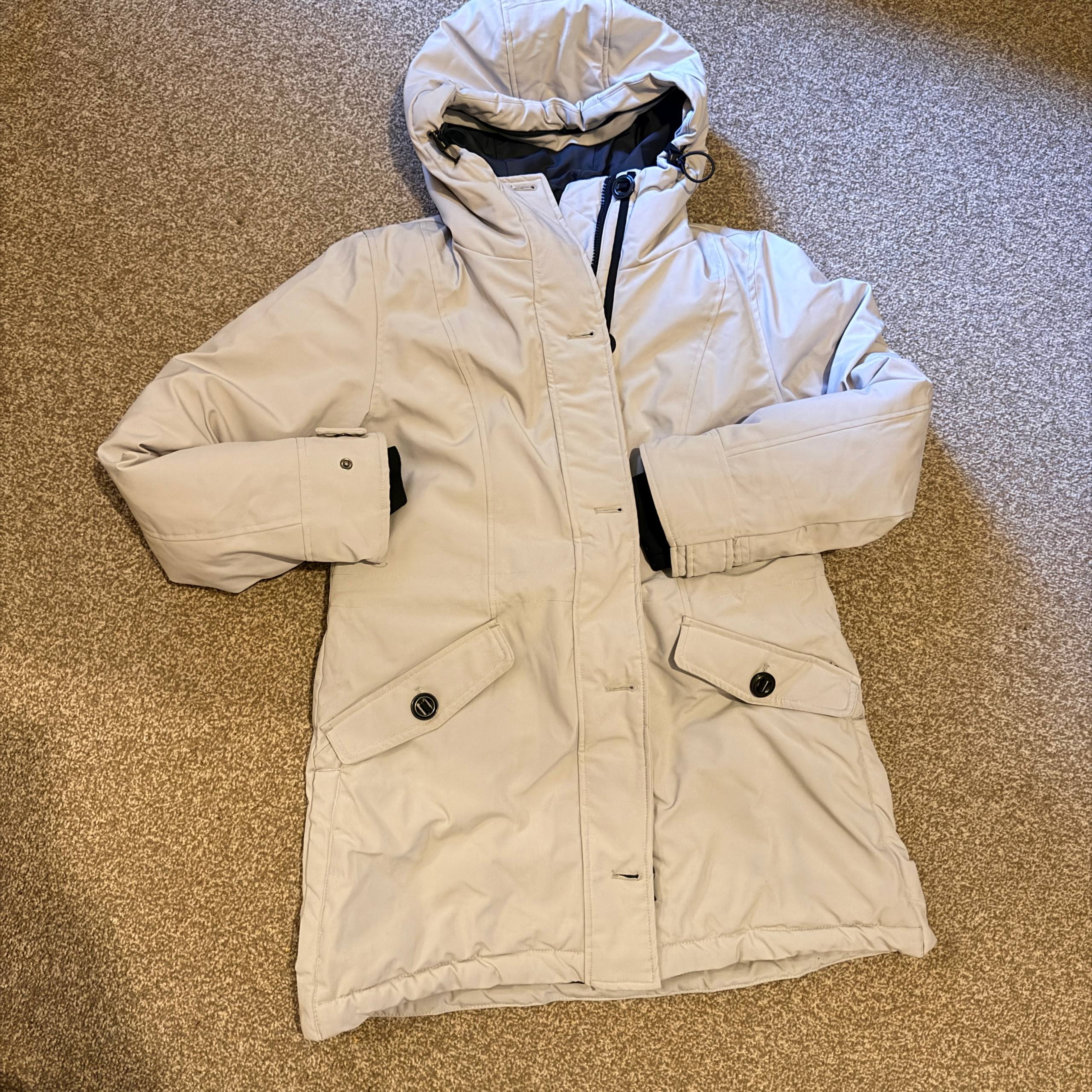 Beige winter coat with a hood on a textured surface