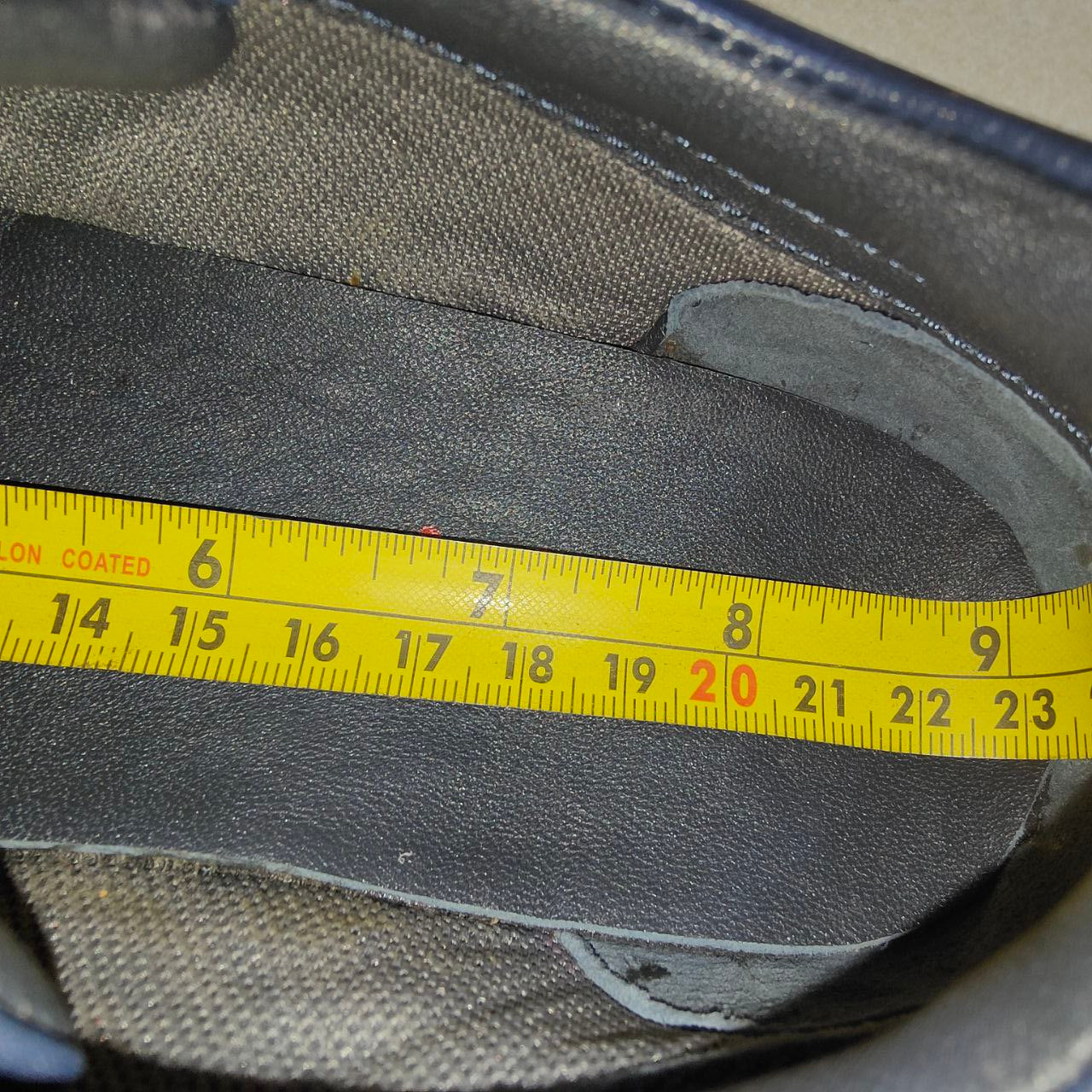 Measurement of a shoe insole using a yellow tape measure.