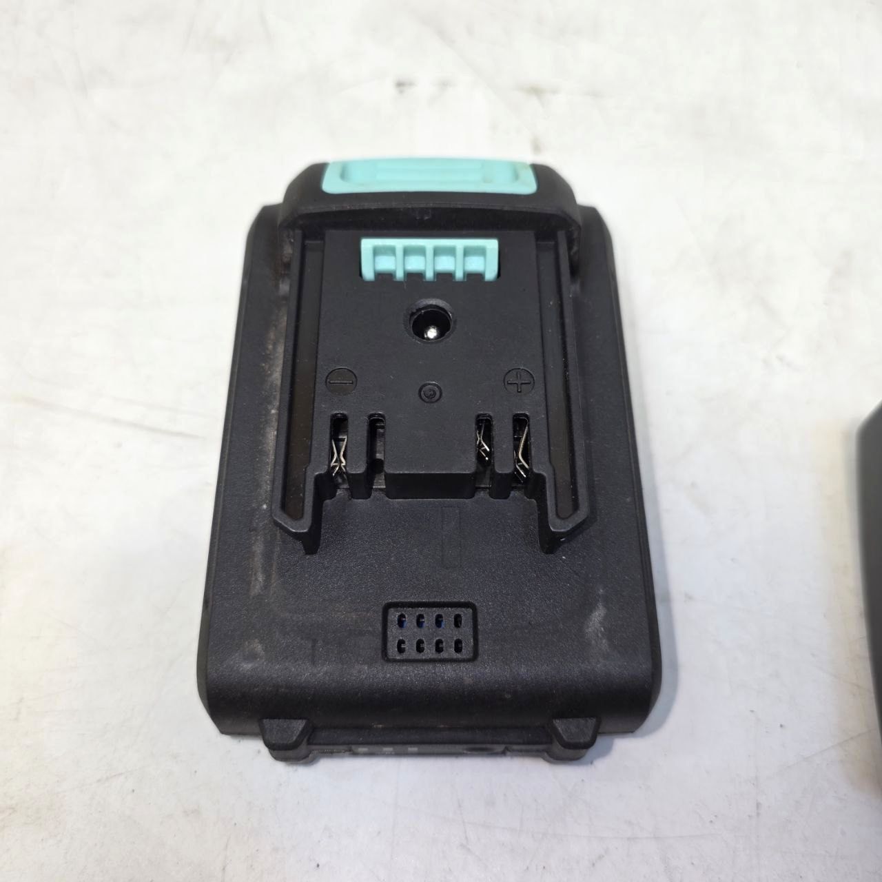 Black battery adapter with green label on a white background