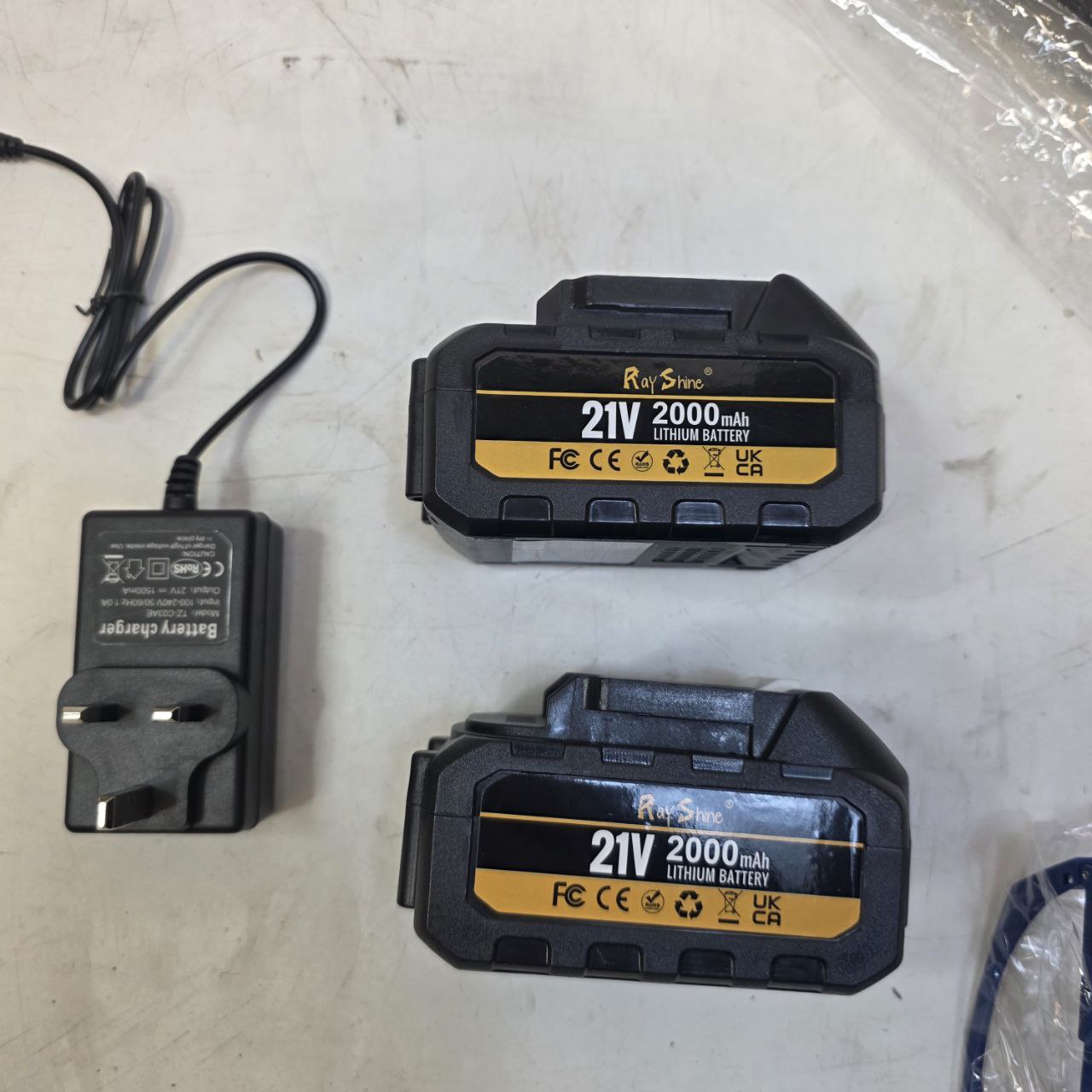 Two 21V 2000mAh lithium batteries and a charger on a white surface